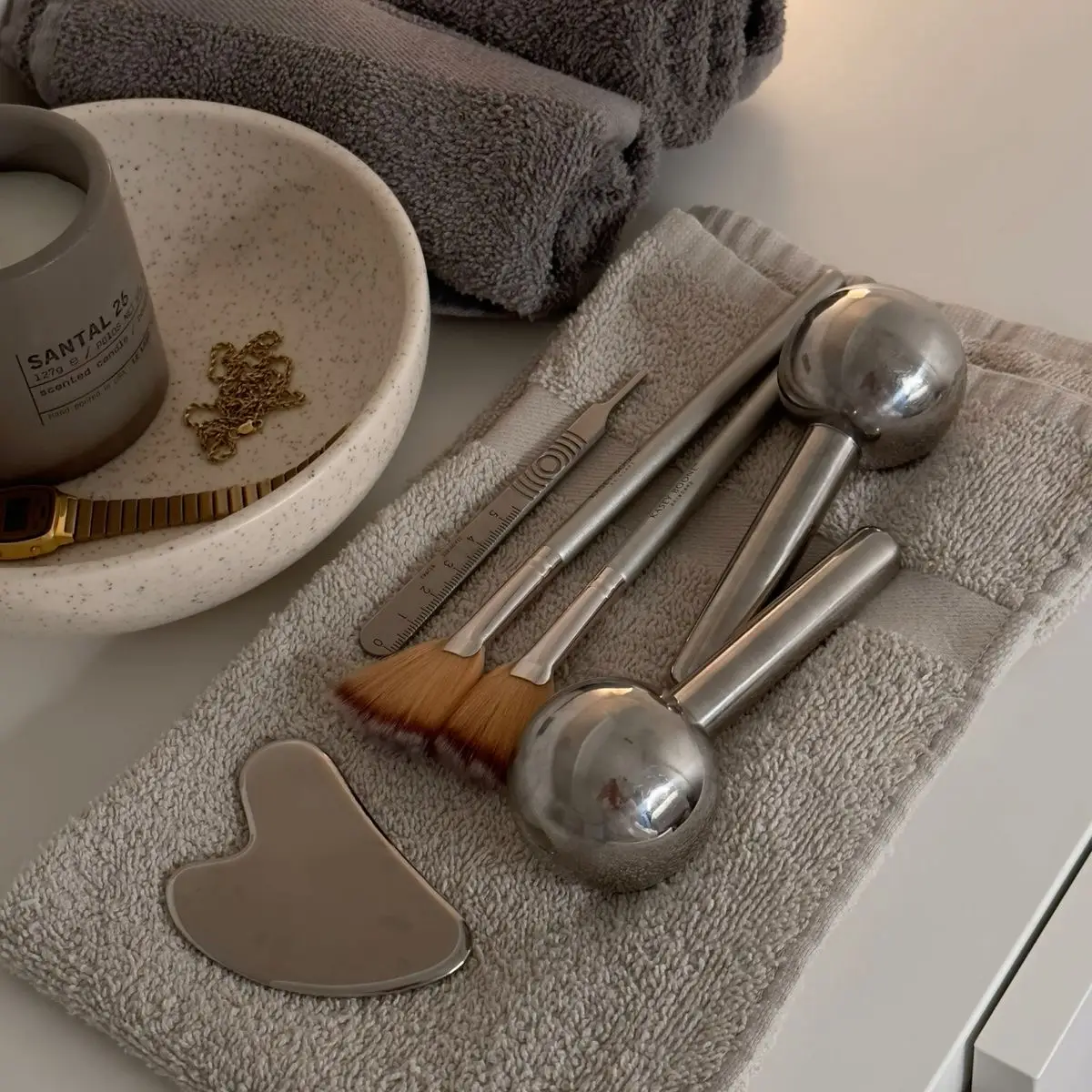 Facial tools, rollers and gua sha laid out on a towel